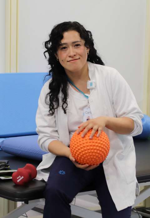 Fysioterapeutti pitelee palloa ja katsoo kameraan.