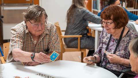 Ikääntyneet pelaavat korttia.
