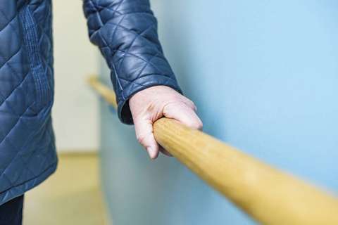 Ikääntynyt tukeutuu kaiteeseen. 