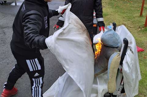 Palavaa, pyörätuolissa istuvaa nukkea sammutetaan sammutuspeitteen avulla. 