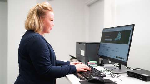 Vaaleahiuksinen henkilö työskentelee tietokoneen ääressä.